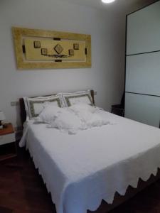 Una cama con sábanas blancas y almohadas en un dormitorio en Marco Romani, en Perugia