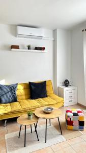 a living room with a yellow couch and two tables at Boutique Apartment Adeje I in Adeje