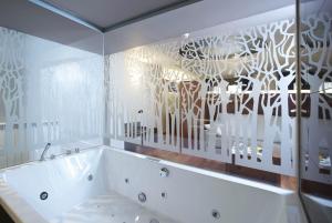 a white bath tub in a bathroom with a window at Hotel Sancho Abarca Petit SPA in Huesca