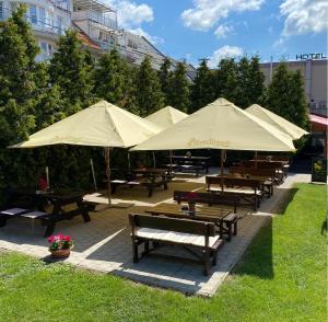 eine Gruppe Picknicktische mit Sonnenschirmen in einem Park in der Unterkunft Hotel 21 in Bratislava