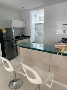 una cocina con 2 sillas blancas y una encimera de cristal en Apartamento Cerca Al Hotel Las Américas, en Cartagena de Indias