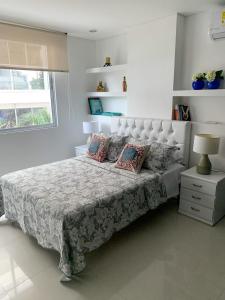 una camera da letto con un grande letto con cuscini sopra di Apartamento Cerca Al Hotel Las Américas a Cartagena de Indias