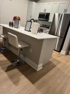 a kitchen with a white counter with chairs and appliances at Towson Elite Apartment in Towson