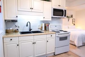 a kitchen with white cabinets and a sink and a bed at Oasis Top Floor Suite with Lake and Mtn View in Harrison Hot Springs