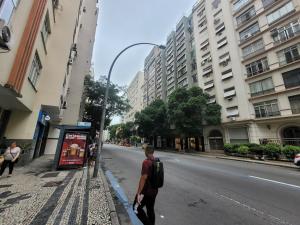 a man with a backpack walking down a city street at SuhcasaCopacabana 48 Spacious in Rio de Janeiro