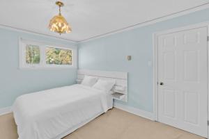 a white bedroom with a bed and a window at Stunning 4BR Cottage with Lake View in Barrie