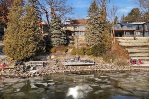 una casa junto a un río con un barco en el agua en Stunning 4BR Cottage with Lake View, en Barrie