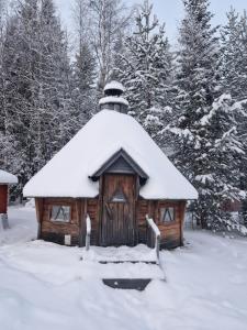 a cabin with a snow covered roof in the snow at Ainola 2 in Syöte