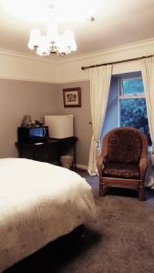 a bedroom with a bed and a chair and a window at Disblair House in Newmachar