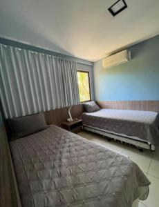 拉巴拉德納聖米格爾的住宿－Apartamento em Barra Bali, Resort de Luxo, Barra de São de Miguel - 223，一间卧室设有两张床和窗户。