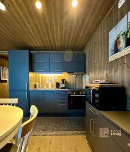 a kitchen with blue cabinets and a table at Super apartment right on the slopes and stadium in Sjusjøen