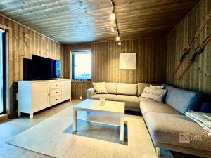 uma sala de estar com um sofá e uma televisão em Super apartment right on the slopes and stadium em Sjusjøen
