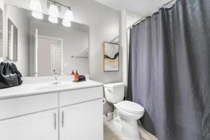 a bathroom with a toilet and a shower curtain at Penthouse Living near DC and Metro in Arlington