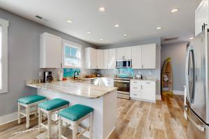 a kitchen with white cabinets and a counter with stools at Surf M' Oceans in Myrtle Beach