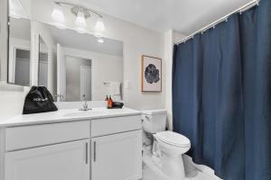 a bathroom with a toilet and a blue shower curtain at Chic DC Getaway Near Metro in Arlington
