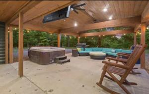 a covered patio with a couch and a hot tub at Deluxe Forest Haven Hot Tub Sleeps 10 in Stephens Gap