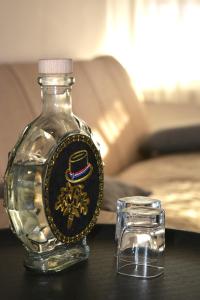 a glass bottle with a sigil on it next to a cup at Apartment Ematours in Požega