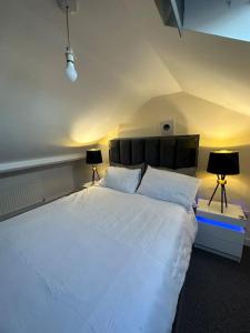 ダービーにあるModern 1 Bed Flat In Derby Cityのベッドルーム(白い大型ベッド、ランプ2つ付)