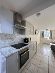 a kitchen with white cabinets and a stove top oven at Modern 1 Bed Flat In Derby City in Derby