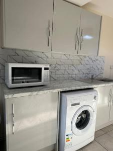 a kitchen with a washing machine and a microwave at Modern 1 Bed Flat In Derby City in Derby