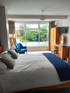 a bedroom with a bed with a blue chair and a window at Breakers Bed and Breakfast in Eastbourne