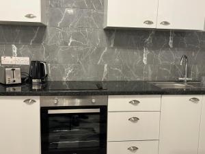 a kitchen with white cabinets and a black counter top at Headington House in Oxford