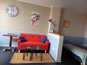 a room with a red couch and a bed at Ambiance vintage pour 2 in Saint-Cyr-sur-Loire