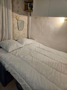 - un lit avec des draps blancs dans une chambre dans l'établissement Studette Rémilly à Versailles, à Versailles
