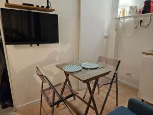 a dining room table with two chairs and a television on a wall at Studette Rémilly à Versailles in Versailles +10 photos