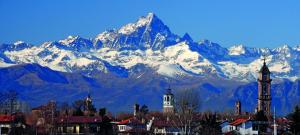a snow covered mountain with a city and a clock tower at L'ORCHIDHEA APARTMENT in Savigliano