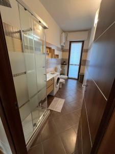 La salle de bains est pourvue d'une douche en verre et de toilettes. dans l'établissement L'ORCHIDHEA APARTMENT, à Savillan