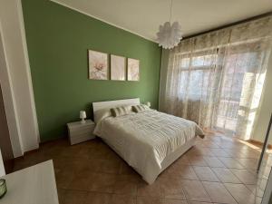 - une chambre avec un lit et un mur vert dans l'établissement L'ORCHIDHEA APARTMENT, à Savillan