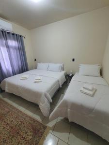 2 camas en una habitación con sábanas blancas en Dein Platz Pousada, en Timbó