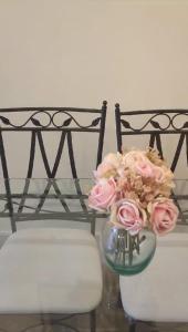 un vase rempli de roses roses assises à côté d'une chaise dans l'établissement Grand studio 29, à Faro
