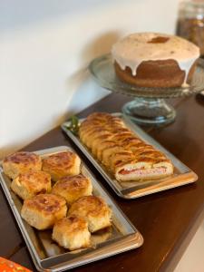 einen Tisch mit zwei Tabletts Gebäck und einem Kuchen in der Unterkunft Pousada do Nica in Fernando de Noronha