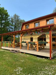 a house with a wooden deck with picnic tables at Dzintara Pirts in Vigale