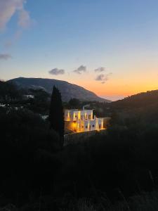 a view of a building with the sunset in the background at Haroupia Hillside Villa in Kalymnos