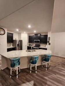 a kitchen with a large counter with blue bar stools at Shella Home in Missouri City