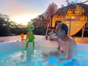 Ein Mann in einem Pool mit Spielzeug in einer Badewanne. in der Unterkunft @chalesdoavohay com banheira hidromassagem aquecida in Sao Jorge