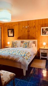 um quarto com uma cama grande e paredes de madeira em KURALEMU Casa de Campo em Curacaví