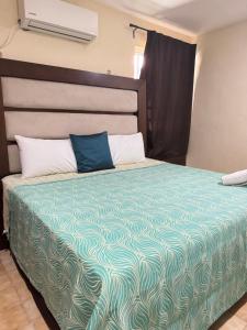 a bedroom with a bed with a blue and white comforter at La Casita de Jonas in Puerto Morelos