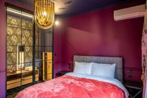 um quarto com uma parede vermelha com uma cama e um lustre em Apartments center em Lárissa