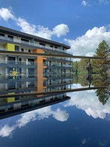 a building with a reflection in the water at Római Ház Apartman in Siófok