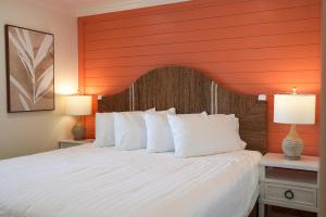 a bedroom with a large white bed with an orange headboard at Manasota Key Resort in Englewood
