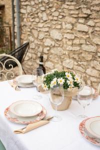 einen Tisch mit Tellern und Gläsern und eine Vase Blumen in der Unterkunft Residenza Borgo Valpolicella in SantʼAmbrogio di Valpolicella