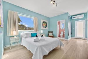 um quarto azul com uma cama branca e uma janela em The New Yorker Miami Hotel em Miami