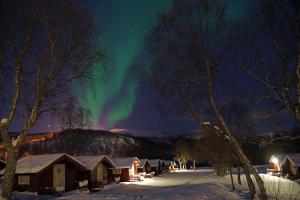 eine Aurora über einer Reihe von Hütten im Schnee in der Unterkunft Sortland Camping og Motell AS in Sortland