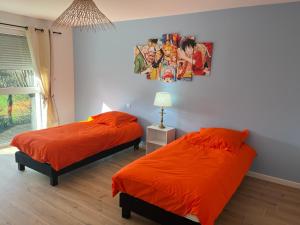 a bedroom with two beds and a painting on the wall at La Perle du petit Rupembert in Wimille