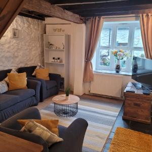 a living room with two couches and a table at Cosy modern cottage by the sea, heart of snowdonia in Llwyngwril