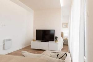 a white living room with a tv and a couch at DIAMOND - Luxusný Apartmán Marco in Podhájska